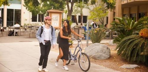 Two students walk together in the Scott Hall courtyard.